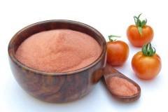 Tomato powder in a wooden bowl with fresh tomatoes isolated on white background